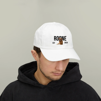 White classic dad cap with "ROONE EST 2024" and dog graphic, worn by man in black hoodie